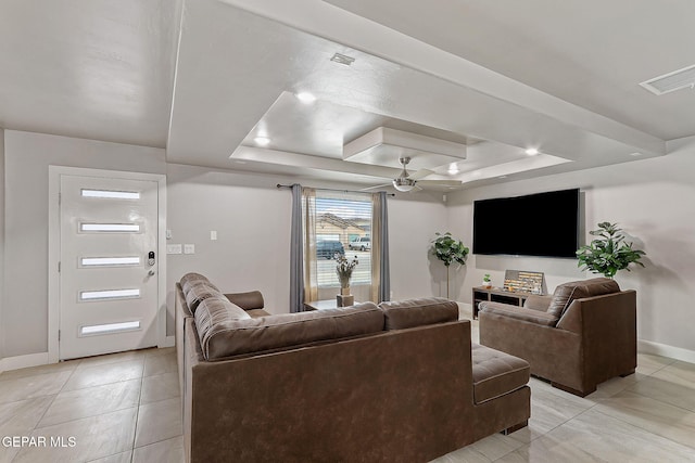 tiled living room with a tray ceiling and ceiling fan