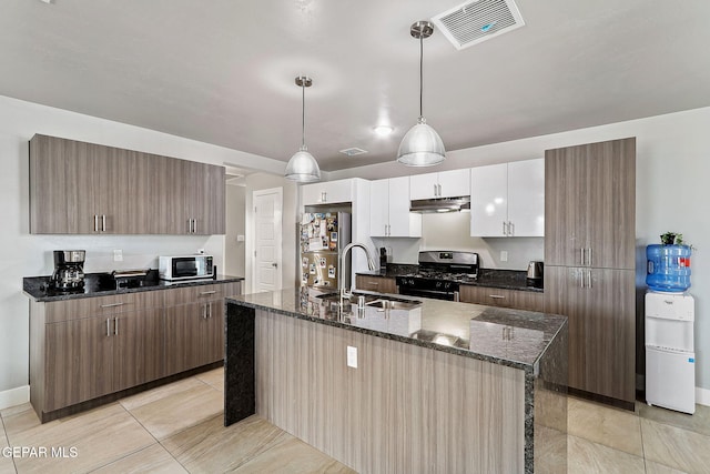 kitchen featuring pendant lighting, a kitchen island with sink, white cabinets, sink, and appliances with stainless steel finishes