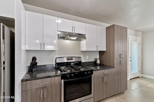 kitchen featuring dark stone countertops, light tile patterned flooring, white cabinets, and stainless steel appliances