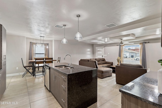 kitchen featuring stainless steel dishwasher, a kitchen island with sink, sink, light tile patterned floors, and decorative light fixtures