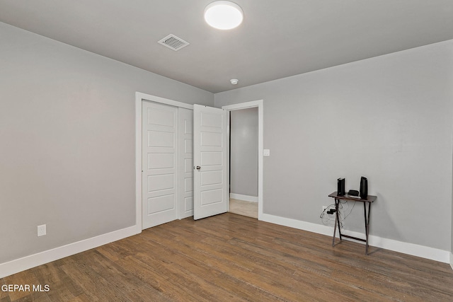 unfurnished bedroom featuring dark hardwood / wood-style flooring and a closet