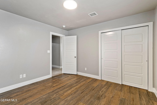 unfurnished bedroom featuring dark hardwood / wood-style flooring and a closet