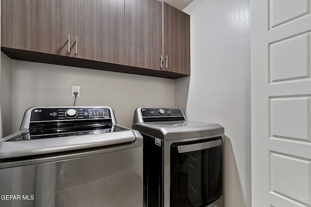 laundry room with washing machine and clothes dryer and cabinets