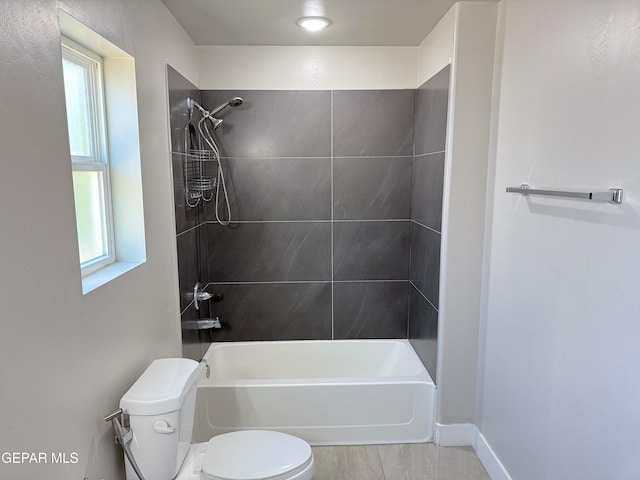 bathroom featuring tile patterned floors, tiled shower / bath, and toilet