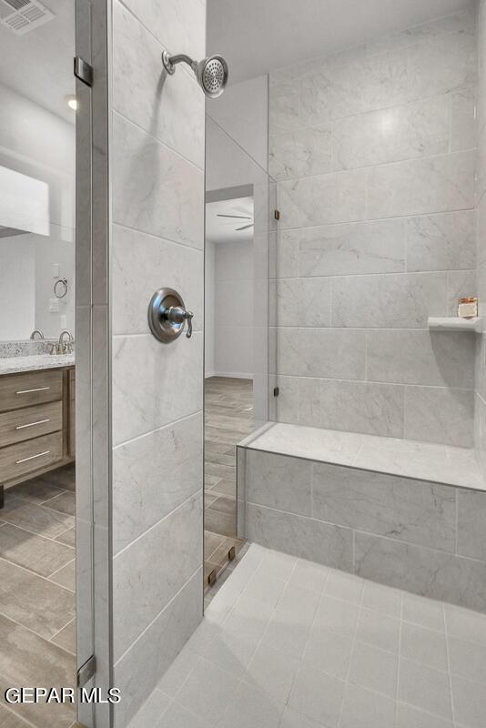 bathroom with a tile shower and vanity