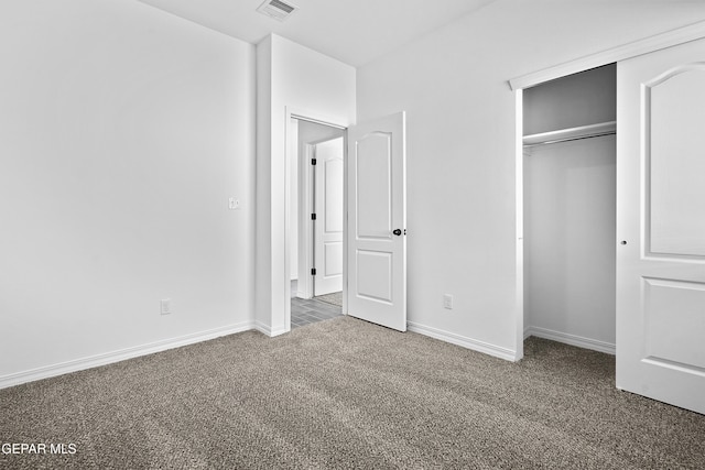 unfurnished bedroom featuring dark carpet and a closet