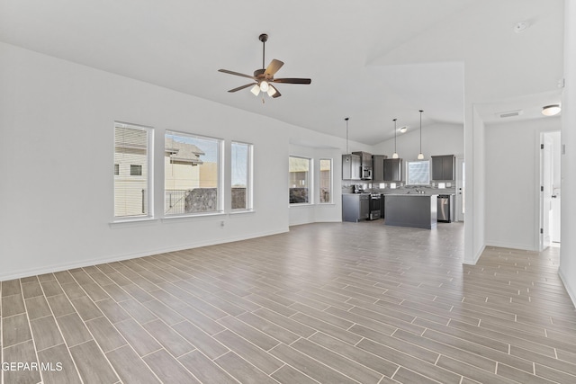 unfurnished living room featuring vaulted ceiling and ceiling fan