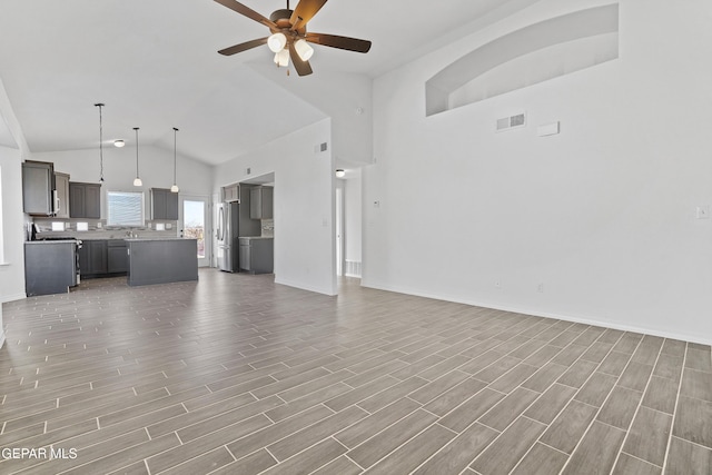 unfurnished living room with high vaulted ceiling and ceiling fan