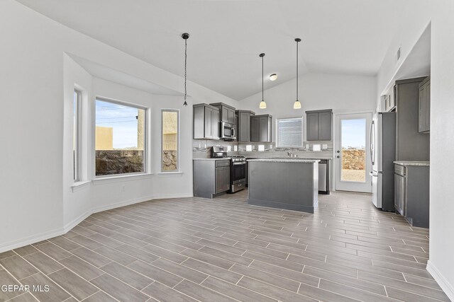 kitchen with gray cabinetry, a center island, lofted ceiling, decorative light fixtures, and stainless steel appliances