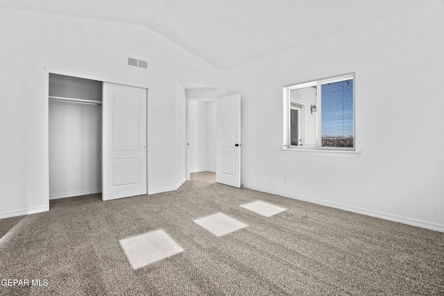 unfurnished bedroom featuring carpet flooring, lofted ceiling, and a closet