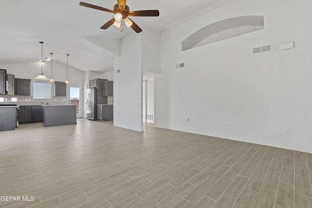 unfurnished living room with ceiling fan, sink, and vaulted ceiling