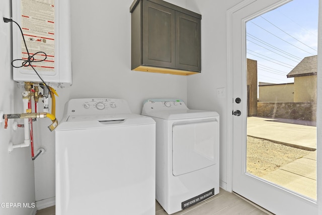 laundry area featuring light tile patterned flooring, cabinets, washing machine and dryer, and water heater