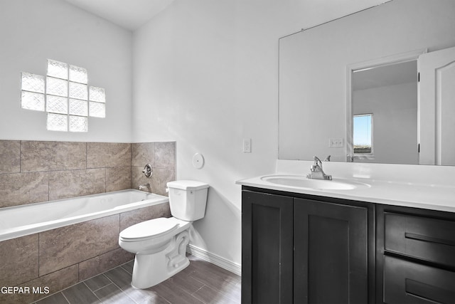 bathroom featuring vanity, tiled bath, and toilet