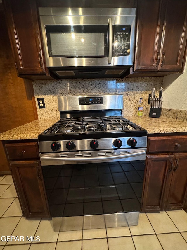 kitchen featuring appliances with stainless steel finishes, tasteful backsplash, light tile patterned floors, and light stone counters