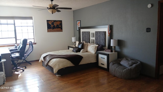 bedroom featuring ceiling fan, wood-type flooring, and a textured ceiling