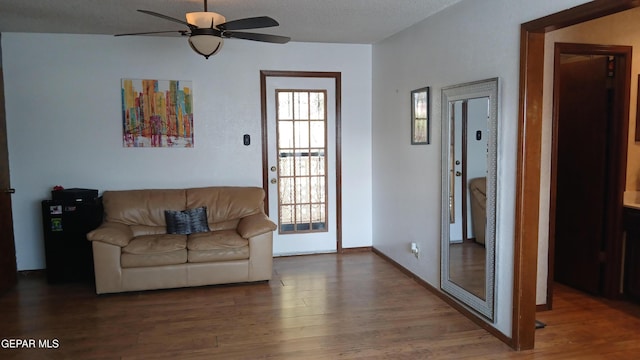 living room featuring dark hardwood / wood-style flooring, a wealth of natural light, and ceiling fan