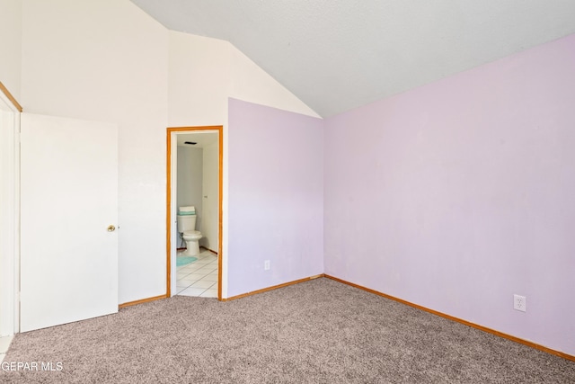 unfurnished bedroom with connected bathroom, light colored carpet, and vaulted ceiling