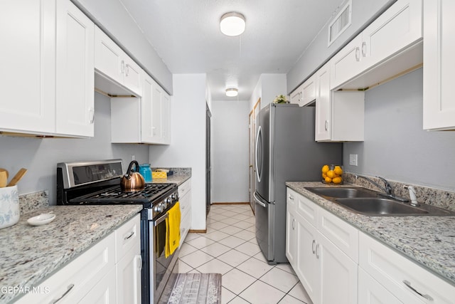 kitchen featuring white cabinets, appliances with stainless steel finishes, light stone countertops, and sink