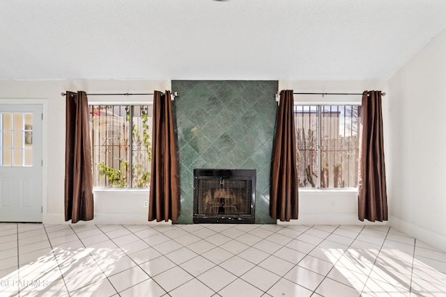 unfurnished living room with a fireplace, light tile patterned floors, and a wealth of natural light