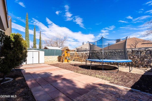 view of patio featuring a playground, a shed, and a trampoline