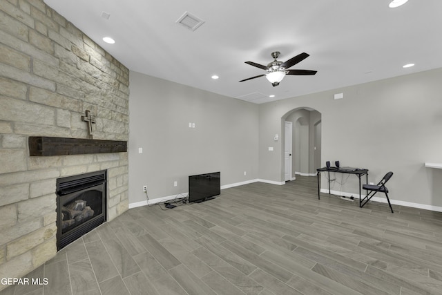 living room featuring a stone fireplace, ceiling fan, and hardwood / wood-style flooring