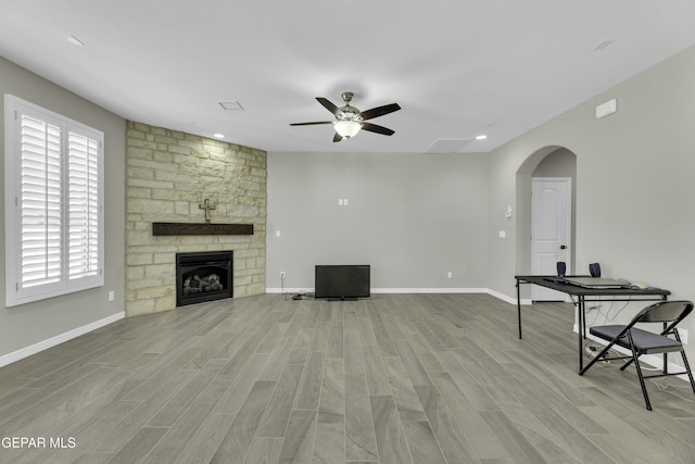 unfurnished living room featuring ceiling fan, a fireplace, and light hardwood / wood-style flooring