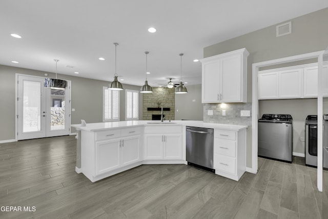 kitchen featuring tasteful backsplash, stainless steel dishwasher, sink, pendant lighting, and white cabinets