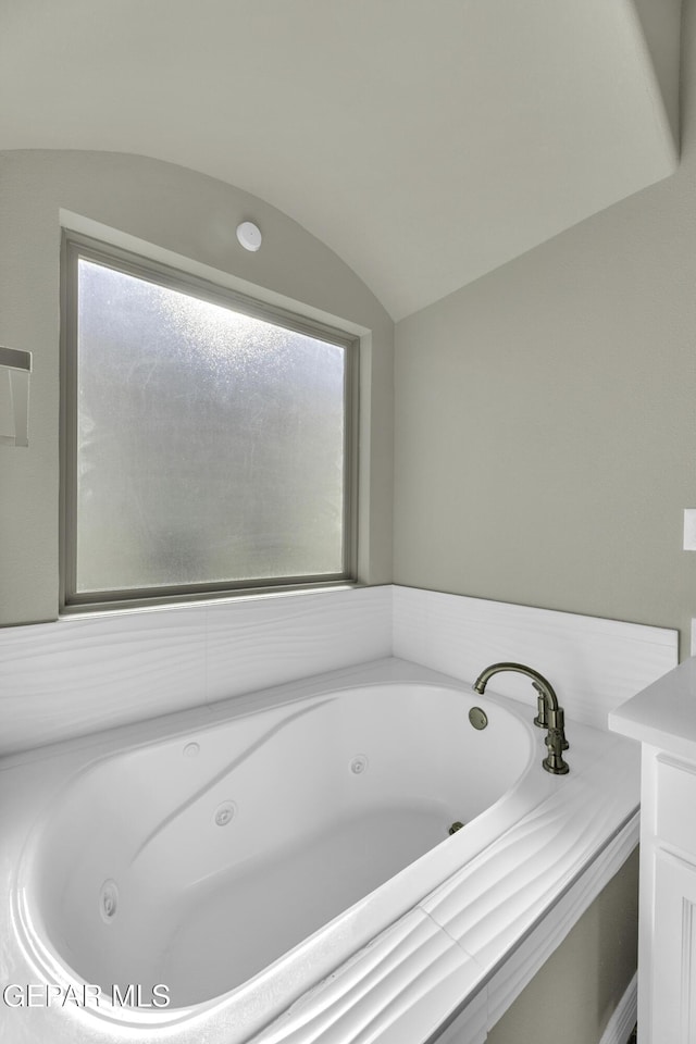 bathroom with vaulted ceiling and a bathtub