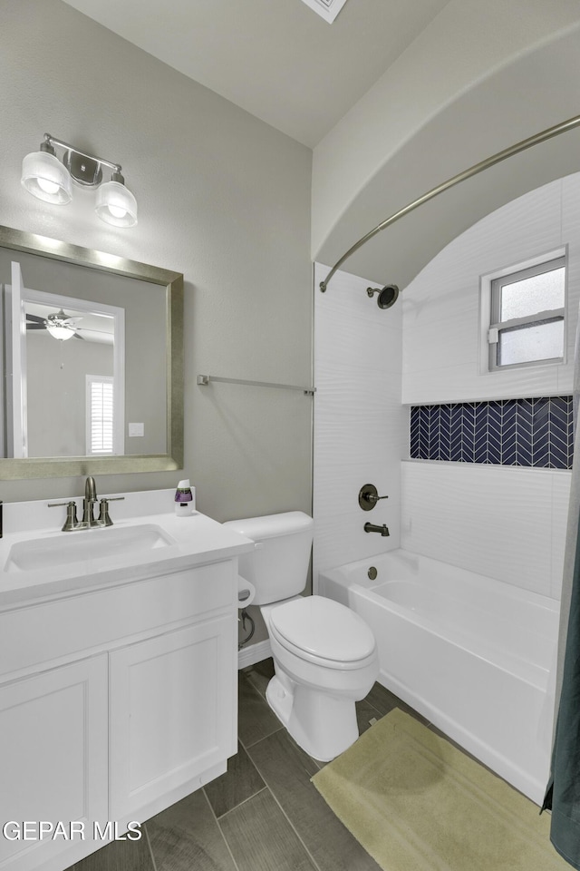 full bathroom with ceiling fan, toilet, tiled shower / bath, and vanity