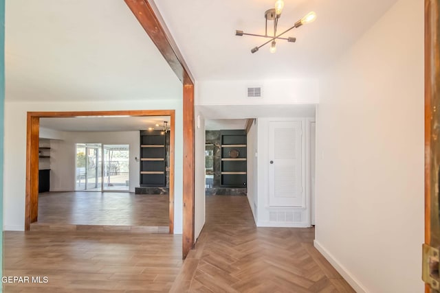 hall with built in shelves, hardwood / wood-style floors, and an inviting chandelier