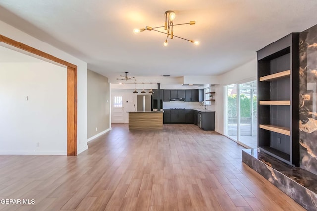 unfurnished living room with hardwood / wood-style floors, a large fireplace, a notable chandelier, and sink