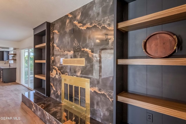 interior space featuring tasteful backsplash, a fireplace, sink, and hardwood / wood-style floors