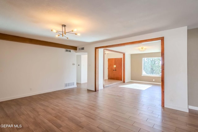 unfurnished room with light hardwood / wood-style floors and a notable chandelier