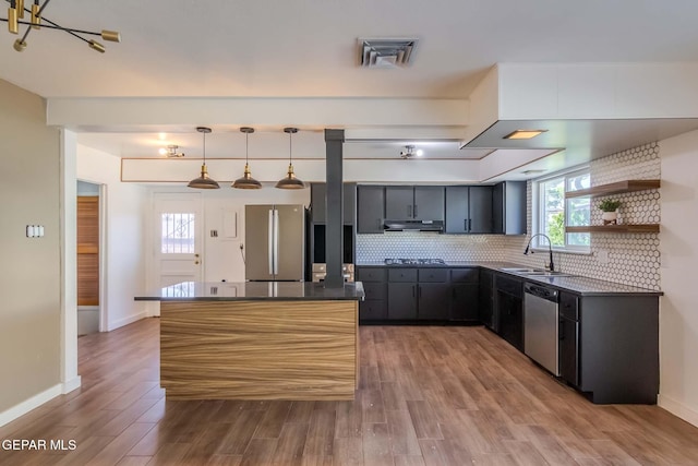 kitchen featuring decorative backsplash, sink, stainless steel appliances, and decorative light fixtures