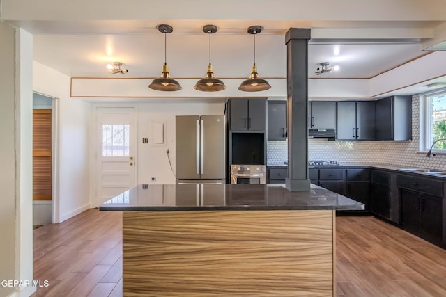 kitchen with hanging light fixtures, decorative backsplash, dark stone countertops, light wood-type flooring, and appliances with stainless steel finishes