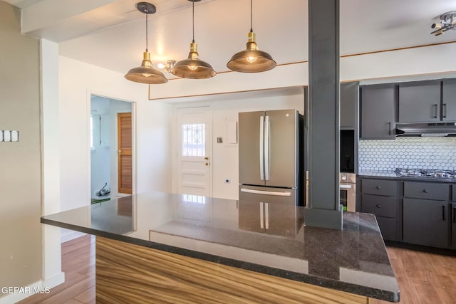 kitchen with tasteful backsplash, light hardwood / wood-style floors, dark stone counters, decorative light fixtures, and appliances with stainless steel finishes