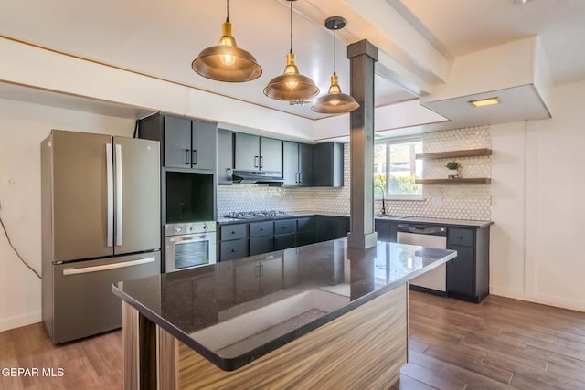 kitchen with tasteful backsplash, stainless steel appliances, wood-type flooring, dark stone countertops, and a breakfast bar area