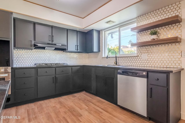 kitchen featuring appliances with stainless steel finishes, light wood-type flooring, tasteful backsplash, and sink