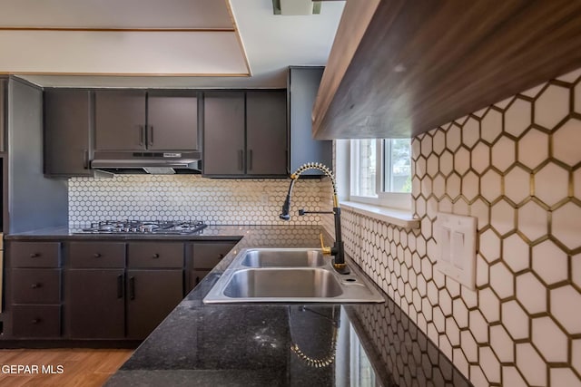 kitchen with stainless steel gas stovetop, light hardwood / wood-style floors, sink, and tasteful backsplash