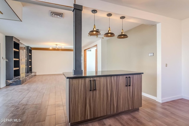 kitchen featuring hardwood / wood-style flooring, pendant lighting, built in features, and a tile fireplace