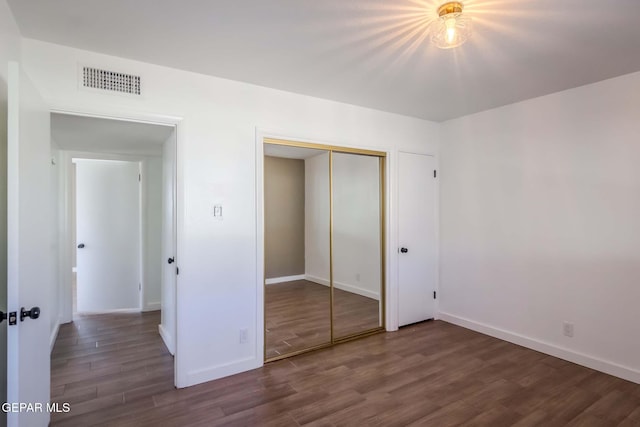 unfurnished bedroom featuring a closet and dark hardwood / wood-style floors