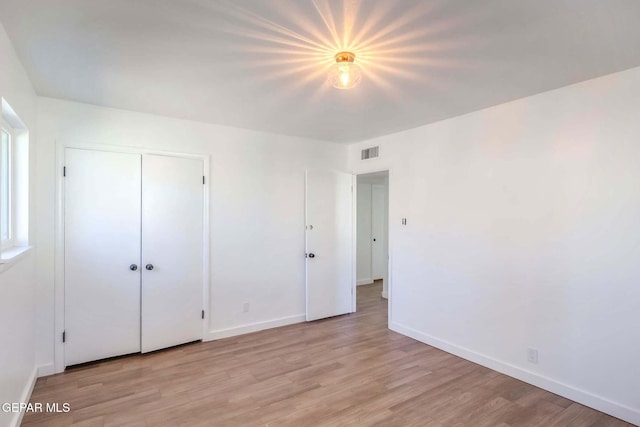 unfurnished bedroom featuring light wood-type flooring and a closet