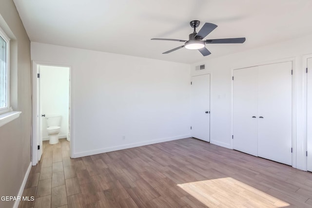 unfurnished bedroom with ceiling fan, ensuite bath, and light hardwood / wood-style flooring