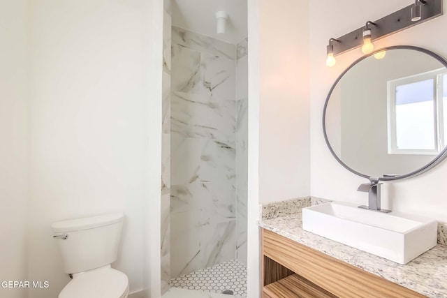 bathroom with vanity, toilet, and tiled shower