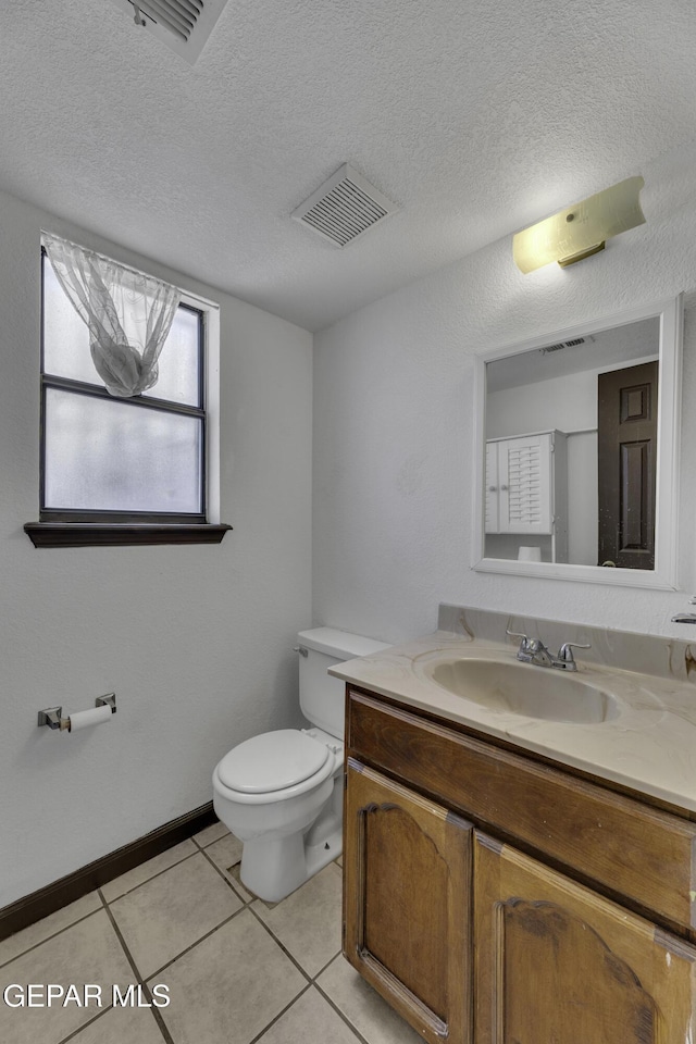 bathroom with tile patterned flooring, vanity, a textured ceiling, and toilet