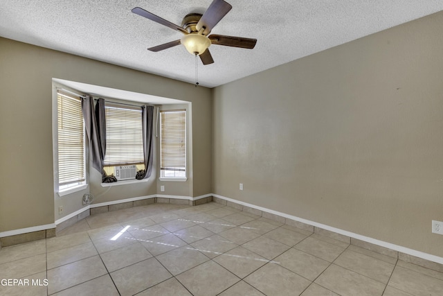 spare room featuring ceiling fan, plenty of natural light, light tile patterned floors, and a textured ceiling