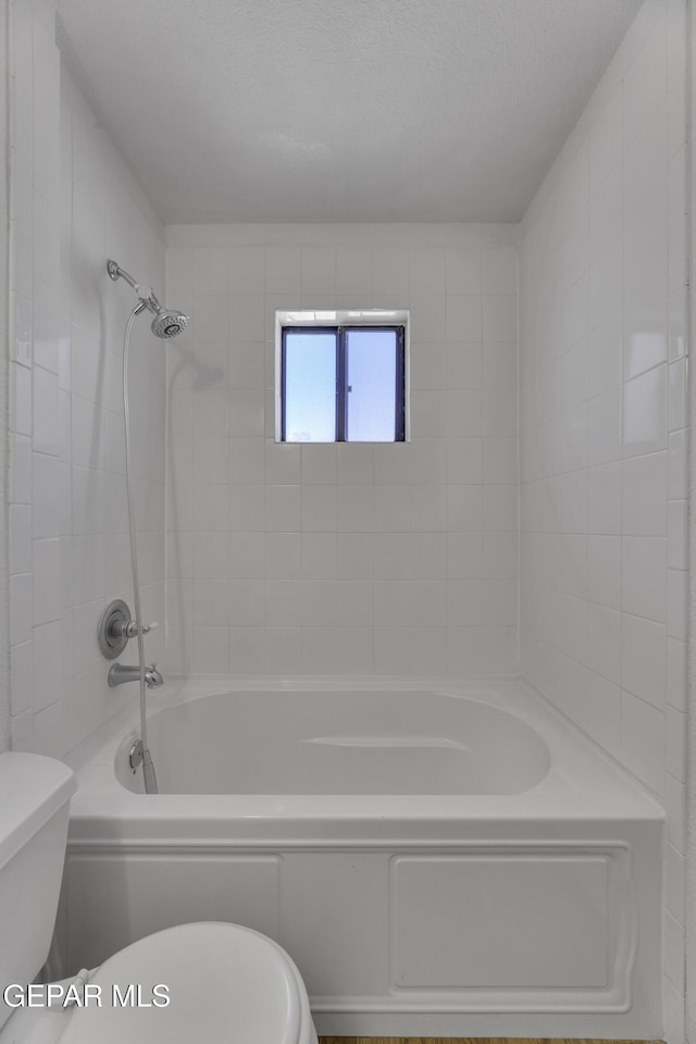 bathroom featuring toilet and tiled shower / bath