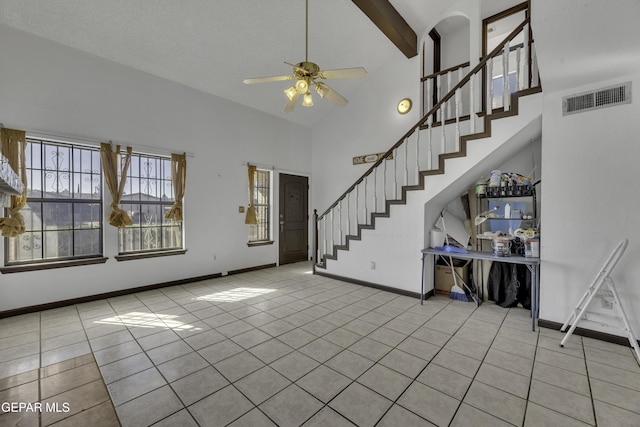 unfurnished living room with a textured ceiling, ceiling fan, light tile patterned floors, beam ceiling, and high vaulted ceiling