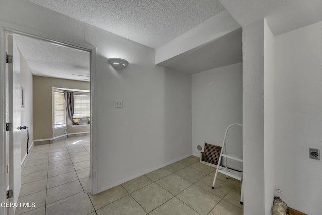 washroom with hookup for an electric dryer, light tile patterned floors, and a textured ceiling