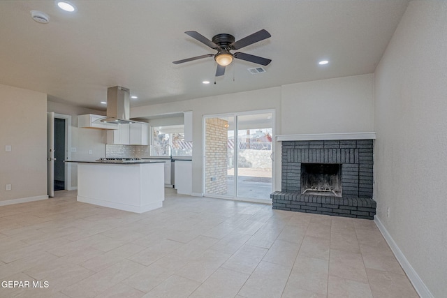 unfurnished living room with ceiling fan and a fireplace